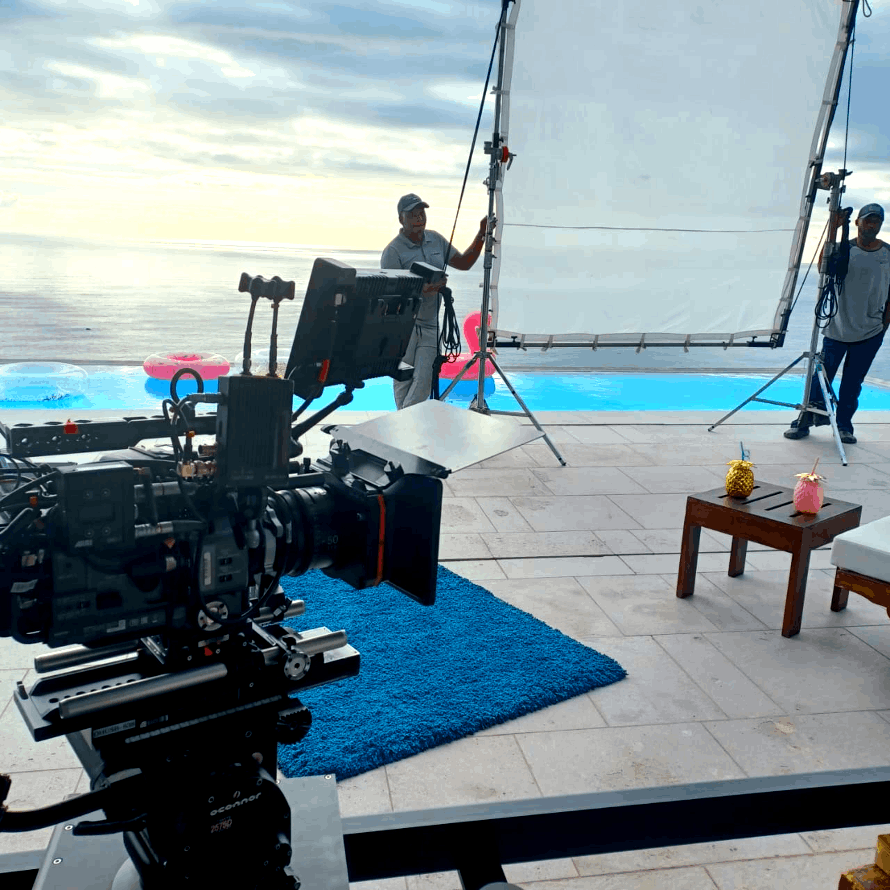 Film crew members holding a scrim in front of a cinema camera